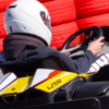 Un individuo con casco conduce un kart en una pista con barreras de neumáticos rojas y blancas, reflejando la emoción de los circuitos de karting en Empuriabrava. - ForTwo - Planes para parejas