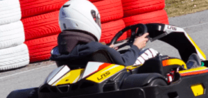 Un individuo con casco conduce un kart en una pista con barreras de neumáticos rojas y blancas, reflejando la emoción de los circuitos de karting en Empuriabrava. - ForTwo - Planes para parejas