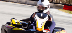 Una persona experimenta el "karting en Empuriabrava" en una pista, compitiendo con un kart amarillo y negro, con casco y agarrando el volante. - ForTwo - Planes para parejas
