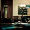 En una oficina con poca luz, que recuerda al Escape Room Misterio del Profesor Waichosky en Zaragoza 🕵️‍♂️, el escritorio de madera de Waichosky está abarrotado de papeles. Una lámpara de tenue luz proyecta sombras sobre un cuadro de Zaragoza, realzando la atmósfera intrigante. - ForTwo - Planes para parejas