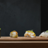 Akiro Barcelona: Un Viaje Gastronómico a Japón para Dos" presenta una variedad de sushi gourmet artísticamente dispuesto sobre una tabla de madera sobre un fondo oscuro, ofreciendo un auténtico viaje culinario japonés. - ForTwo - Planes para parejas