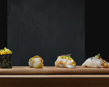 Akiro Barcelona: Un Viaje Gastronómico a Japón para Dos" presenta una variedad de sushi gourmet artísticamente dispuesto sobre una tabla de madera sobre un fondo oscuro, ofreciendo un auténtico viaje culinario japonés. - ForTwo - Planes para parejas