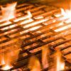 Primer plano de una parrilla llameante con intensas llamas anaranjadas que abrazan las barras de metal, convirtiéndola en "El Paraíso de la Carne en Zaragoza" para los amantes de la carne. - ForTwo - Planes para parejas