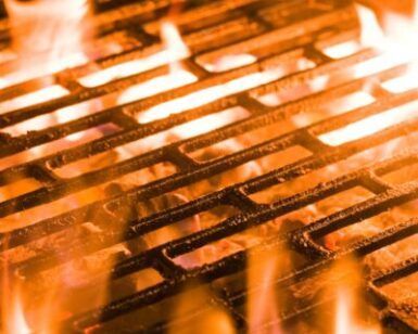 Primer plano de una parrilla llameante con intensas llamas anaranjadas que abrazan las barras de metal, convirtiéndola en "El Paraíso de la Carne en Zaragoza" para los amantes de la carne. - ForTwo - Planes para parejas