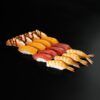Un fondo negro realza una elegante bandeja de nigiri de camarones, atún, mango y anguila. «Cena japonesa en Más que Sushi» ofrece un auténtico festín para los sentidos. - ForTwo - Planes para parejas