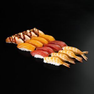 Un fondo negro realza una elegante bandeja de nigiri de camarones, atún, mango y anguila. «Cena japonesa en Más que Sushi» ofrece un auténtico festín para los sentidos. - ForTwo - Planes para parejas