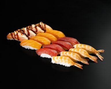 Un fondo negro realza una elegante bandeja de nigiri de camarones, atún, mango y anguila. «Cena japonesa en Más que Sushi» ofrece un auténtico festín para los sentidos. - ForTwo - Planes para parejas