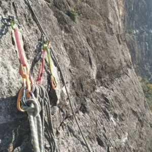 Un Curso de vía ferrata en Morata de Jalón cuenta con cuerdas para escalar y mosquetones asegurados a un acantilado rocoso bajo un cielo despejado para una experiencia de aventura. - ForTwo - Planes para parejas