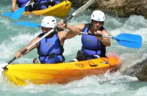 Dos personas con cascos y chalecos salvavidas azules navegan en kayak por los rápidos del Río Gállego en un Descenso en Canoa amarillo. - ForTwo - Planes para parejas