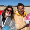 Dos personas con equipo de protección están al aire libre en un soleado día de Zaragoza, sonriendo y sosteniendo globos de colores con texto. Disfrutan de Destructoterapia en Zaragoza, un enfoque terapéutico único que brinda alegría y sanación. - ForTwo - Planes para parejas