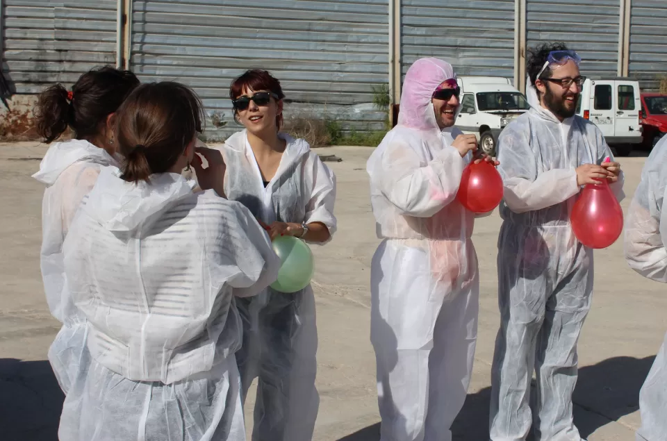 Los participantes vestidos con trajes de protección y gafas protectoras sostienen globos mientras permanecen afuera en un día soleado en Zaragoza, durante un evento de Destructoterapia en Zaragoza. - ForTwo - Planes para parejas