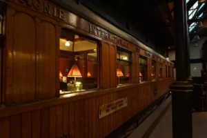 El interior del vagón de tren de madera vintage luce la palabra "Internacional" en el lateral y faroles rojos, creando un ambiente de misterio al estilo Cluedo. Es como viajar a otra época con Escapismo y Cluedo en Zaragoza. - ForTwo - Planes para parejas