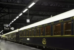 El tren Orient Express descansa sobre una plataforma poco iluminada con sus elegantes vagones antiguos susurrando historias de misterio como "Escapismo y Cluedo en Zaragoza" bajo un techo industrial. - ForTwo - Planes para parejas