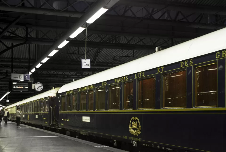 El tren Orient Express descansa sobre una plataforma poco iluminada con sus elegantes vagones antiguos susurrando historias de misterio como "Escapismo y Cluedo en Zaragoza" bajo un techo industrial. - ForTwo - Planes para parejas