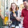Gente disfrutando de tapas y bebidas en una mesa al aire libre en Zaragoza, sonriendo y charlando como si acabaran de visitar el Mercado de Mediodía y Tapas de Zaragoza. - ForTwo - Planes para parejas