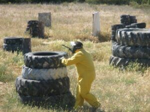 En los campos de hierba de Murillo de Gállego, cerca de Zaragoza, alguien con traje y casco amarillo juega al paintball con destreza, cubriéndose detrás de neumáticos apilados. - ForTwo - Planes para parejas