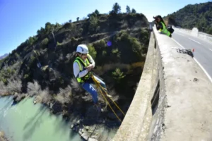 Una persona con equipo de seguridad disfruta del Puenting en Murillo de Gállego desde un puente, mientras otra captura el emocionante descenso desde arriba. - ForTwo - Planes para parejas