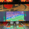 La bolera rebosa de diversión mientras las pantallas digitales muestran un partido de fútbol. Se colocan bolos en cada carril, mientras algunos visitantes se sumergen en emocionantes experiencias con SpeedPark: Karts, Realidad Virtual y Diversión. - ForTwo - Planes para parejas