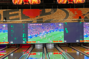 La bolera rebosa de diversión mientras las pantallas digitales muestran un partido de fútbol. Se colocan bolos en cada carril, mientras algunos visitantes se sumergen en emocionantes experiencias con SpeedPark: Karts, Realidad Virtual y Diversión. - ForTwo - Planes para parejas