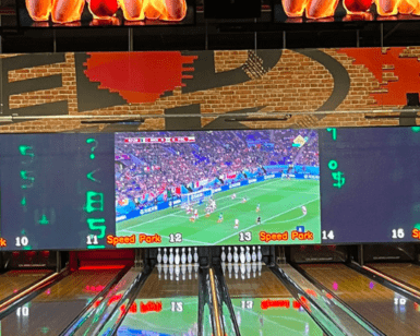 La bolera rebosa de diversión mientras las pantallas digitales muestran un partido de fútbol. Se colocan bolos en cada carril, mientras algunos visitantes se sumergen en emocionantes experiencias con SpeedPark: Karts, Realidad Virtual y Diversión. - ForTwo - Planes para parejas