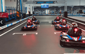 SpeedPark: Karts, Realidad Virtual y Diversión alinea los karts en una pista cubierta con un letrero DEPART ARRIVEE en lo alto, que promete diversión. - ForTwo - Planes para parejas