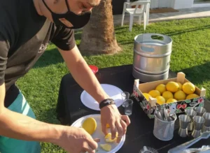 En una escena que recuerda al Taller-show de coctelería de Zaragoza, un individuo enmascarado corta limones con destreza al aire libre sobre una mesa con un barril y una abundante caja de sabrosos tesoros. - ForTwo - Planes para parejas