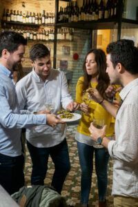 En el acogedor ambiente de Zaragoza, cuatro personas participan en el "Tour de Tapas Nocturno en Zaragoza", brindando y disfrutando de aperitivos como si estuvieran en un delicioso tour de tapas. - ForTwo - Planes para parejas