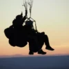 Silueta de dos personas disfrutando de un vuelo en parapente en Lucía al atardecer, con el horizonte escénico de fondo. - ForTwo - Planes para parejas