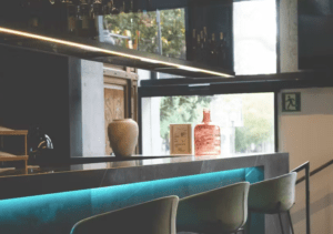 B-Heaven Rooftop Barcelona cuenta con un interior moderno con un mostrador azul brillante, taburetes elegantes, jarrones decorativos y amplias ventanas. - ForTwo - Planes para parejas