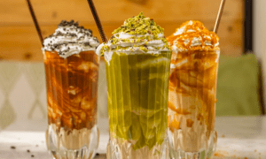El "Brunch más original en Barcelona" consta de tres batidos con crema batida, virutas de chocolate, pistachos y salsa de caramelo servidos en vasos altos, ideales para el brunch. - ForTwo - Planes para parejas