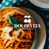 Un plato de pasta con salsa y queso se encuentra sobre una mesa, representando la esencia de una "Cena romántica con auténtica cocina italiana", con el logo de Dolcevita Gusto Italiano superpuesto a la imagen. - ForTwo - Planes para parejas