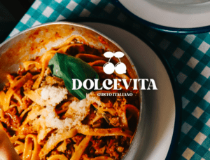 Un plato de pasta con salsa y queso se encuentra sobre una mesa, representando la esencia de una "Cena romántica con auténtica cocina italiana", con el logo de Dolcevita Gusto Italiano superpuesto a la imagen. - ForTwo - Planes para parejas