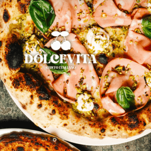 Primer plano de una pizza gourmet con embutidos, albahaca, queso y pistachos: un ejemplo perfecto de una auténtica cena romántica con auténtica cocina italiana. Texto "DOLCEVITA" superpuesto. - ForTwo - Planes para parejas