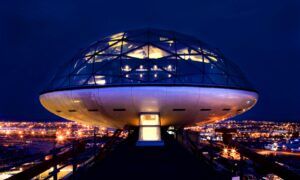 Un edificio futurista en forma de cúpula ilumina la noche contra las luces de la ciudad, ofreciendo una Cena romántica con vistas panorámicas en Barcelona. - ForTwo - Planes para parejas