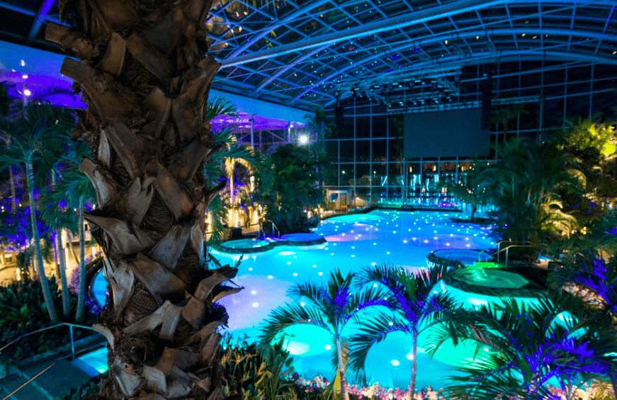 Escapada a Bucarest y al spa más grande de Europa" cuenta con una lujosa piscina tropical cubierta con palmeras y brillantes aguas azules bajo una magnífica cúpula de cristal, que ofrece una encantadora escapada al estilo europeo en el corazón de Bucarest por la noche. - ForTwo - Planes para parejas