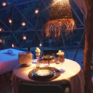 Disfrute de una cena romántica en una cúpula tenuemente iluminada, iluminada por una lámpara de mimbre brillante y una mesa elegante, ideal para una escapada romántica cerca de Barcelona. - ForTwo - Planes para parejas