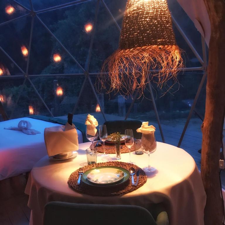 Disfrute de una cena romántica en una cúpula tenuemente iluminada, iluminada por una lámpara de mimbre brillante y una mesa elegante, ideal para una escapada romántica cerca de Barcelona. - ForTwo - Planes para parejas