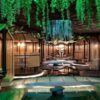 Un interior de restaurante moderno con cabinas de madera, vegetación colgante e iluminación ambiental crea una atmósfera serena similar a Thai Oasiz: Un viaje gastronómico a Tailandia. - ForTwo - Planes para parejas