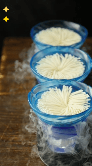 Tres cuencos azules con delicados fideos enrollados crean un ambiente sereno y brumoso sobre una superficie de madera oscura, que evoca un auténtico "Vive una experiencia china en laowanghotpot". - ForTwo - Planes para parejas